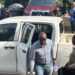 Former LTA chair Abdullai Kamara escorted by officers as he exits a prison transport vehicle after bond approval in Monrovia.