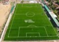 Aerial view of Liberia Football Association’s new FIFA-approved football pitch in Gompa, Nimba County, featuring lush green turf, lined markings, and spectator stands.