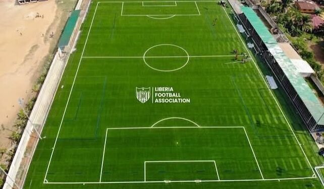 Aerial view of Liberia Football Association’s new FIFA-approved football pitch in Gompa, Nimba County, featuring lush green turf, lined markings, and spectator stands.