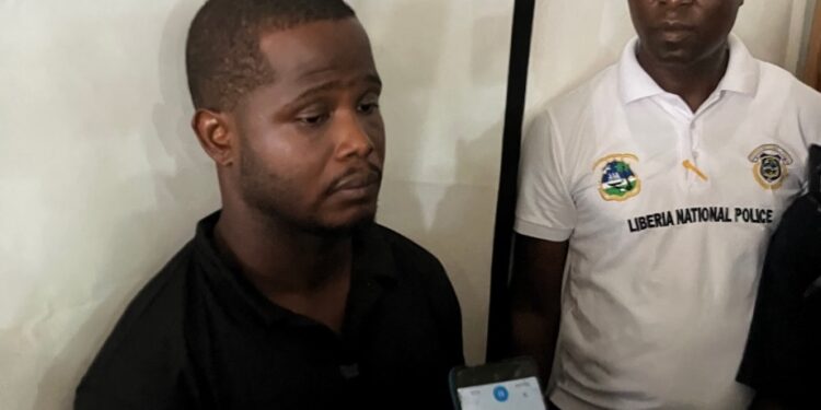 Defendant Lawrence K. Williams appears with police officers in Monrovia ahead of his Unity Party crash trial, nearly two years after the incident.