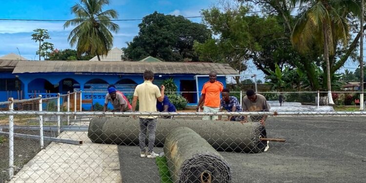 Workers install synthetic turf at Bible Way Mission School in Liberia as part of an LFA and FIFA pilot project to boost grassroots football.