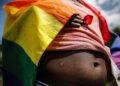 lose-up of a person draped in a rainbow pride flag, symbolizing LGBTQ+ identity and vulnerability amid growing human rights concerns in Liberia.