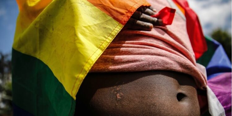 lose-up of a person draped in a rainbow pride flag, symbolizing LGBTQ+ identity and vulnerability amid growing human rights concerns in Liberia.