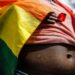 lose-up of a person draped in a rainbow pride flag, symbolizing LGBTQ+ identity and vulnerability amid growing human rights concerns in Liberia.