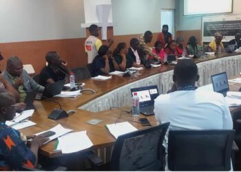 Participants of the multistakeholder dialogue in Monrovia seated in a conference room during discussions on land governance jobs for graduates, followed by a group photo outside with civil society leaders, educators, students, and international partners.