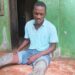 Injured House worker Alvin N. Jabbeh sits on the floor showing his injured legs after allegedly being assaulted at Deputy Speaker Thomas Fallah’s residence in Johnsonville