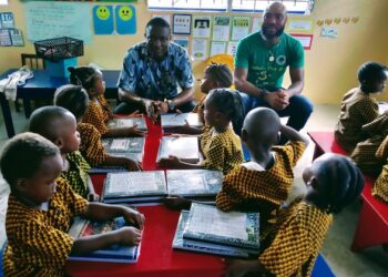 Custodian Urey Paye of Embassy Tree interacts with young students receiving donated copybooks during the back-to-school drive in Paynesville