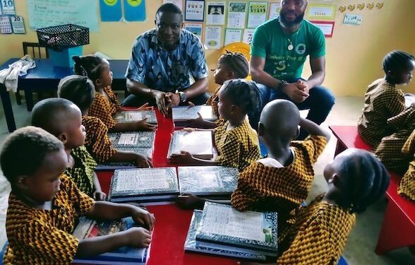 Custodian Urey Paye of Embassy Tree interacts with young students receiving donated copybooks during the back-to-school drive in Paynesville