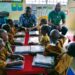 Custodian Urey Paye of Embassy Tree interacts with young students receiving donated copybooks during the back-to-school drive in Paynesville