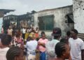 Residents gather outside a burned house on Caldwell Back Road in Monrovia after a late-night fire killed six people, including two children