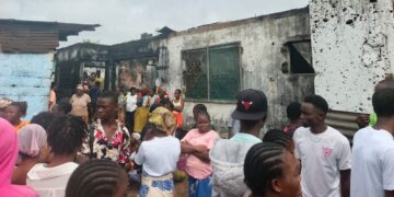 Residents gather outside a burned house on Caldwell Back Road in Monrovia after a late-night fire killed six people, including two children
