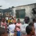 Residents gather outside a burned house on Caldwell Back Road in Monrovia after a late-night fire killed six people, including two children