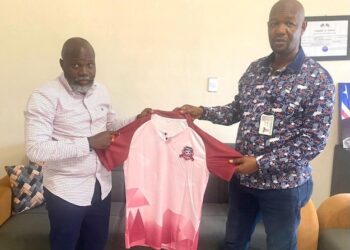 Paynesville Mayor Robert S. Bestman II presents a team jersey to Paynesville FC President Hilary Sackie during the club’s recognition as the official football team of the city.