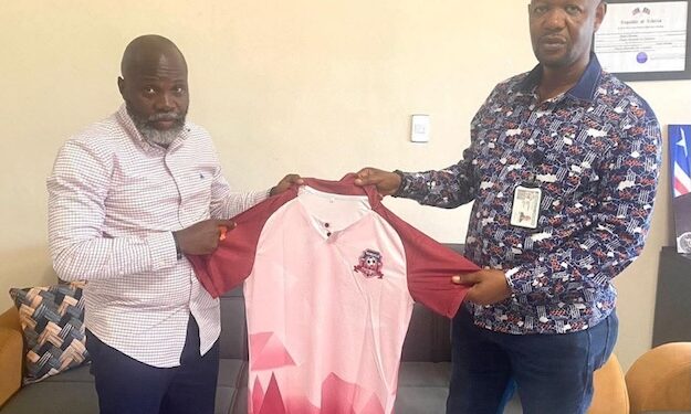 Paynesville Mayor Robert S. Bestman II presents a team jersey to Paynesville FC President Hilary Sackie during the club’s recognition as the official football team of the city.