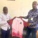 Paynesville Mayor Robert S. Bestman II presents a team jersey to Paynesville FC President Hilary Sackie during the club’s recognition as the official football team of the city.