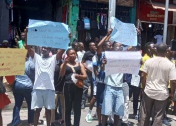 Street vendors in Monrovia hold placards during a protest on Michelin Street, appealing to President Boakai for relief after police raids disrupted their trade