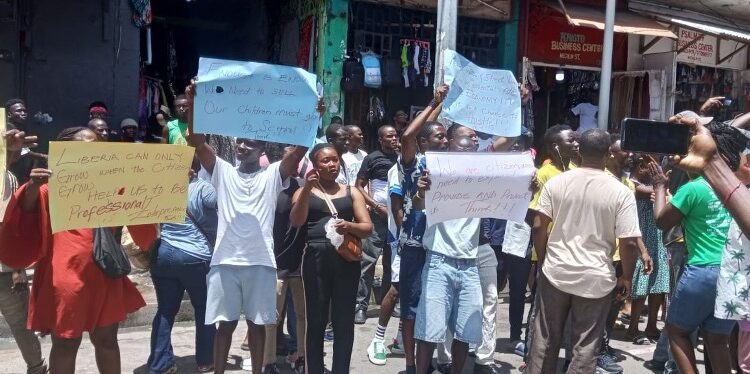 Street vendors in Monrovia hold placards during a protest on Michelin Street, appealing to President Boakai for relief after police raids disrupted their trade