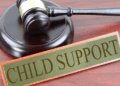 A wooden gavel beside a sign reading “Child Support,” symbolizing legal action against child support neglect in Grand Kru County, Liberia