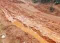 A muddy, impassable rural road in Garyea Clan, Bong County, showing deep erosion and stagnant water after heavy rains