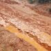 A muddy, impassable rural road in Garyea Clan, Bong County, showing deep erosion and stagnant water after heavy rains