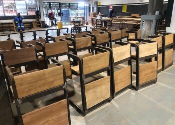 Rows of newly built wooden-and-metal classroom chairs at the Monrovia Vocational Training Center workshop, produced under the “One Chair, One Child” program funded by salaries withheld from suspended Liberian government officials