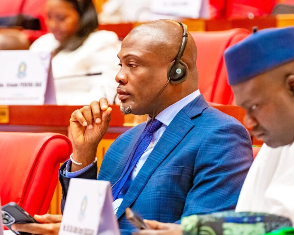 A man wearing a blue traditional outfit seated at a conference, identified as Representative Taa Wongbe of Nimba County District 9.
