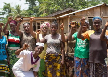 Rural women in Western Liberia raise their hands in solidarity during a community meeting, calling on President Joseph Boakai for financial empowerment and market support