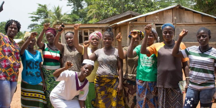 Rural women in Western Liberia raise their hands in solidarity during a community meeting, calling on President Joseph Boakai for financial empowerment and market support