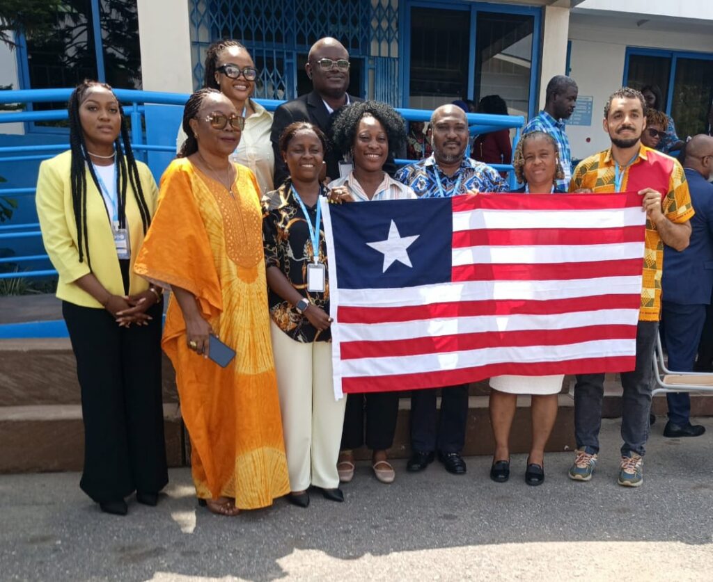 Liberian delegation and Ambassador Musu Jatu Ruhle pose with national flag at Kaizen public-sector training in Accra, Ghana.