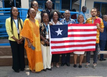 Liberian delegation and Ambassador Musu Jatu Ruhle pose with national flag at Kaizen public-sector training in Accra, Ghana.