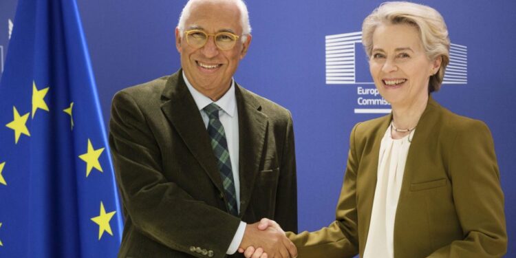 Two senior officials shaking hands in front of European Union flags during a diplomatic meeting