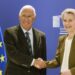 Two senior officials shaking hands in front of European Union flags during a diplomatic meeting