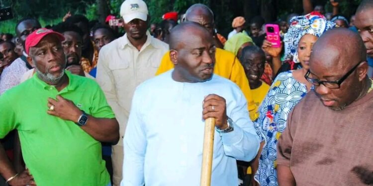 A group of people gathered outdoors, with one person holding a stick while others stand and observe during a community or inspection event