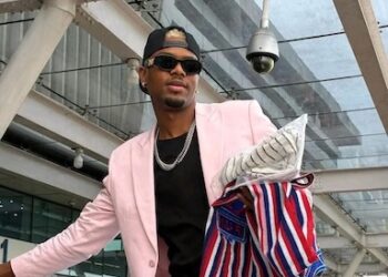 Jzyno standing through vehicle sunroof as fans welcome him at RIA during massive homecoming celebration.