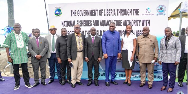 A group of people standing together at an outdoor commissioning ceremony for a national fisheries project