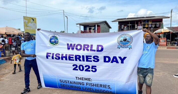 Two participants hold a banner reading “World Fisheries Day 2025” during Liberia’s first-ever national celebration.