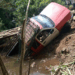 A pickup truck shown partially fallen or damaged on a deteriorated wooden bridge in a rural area, drawing attention to poor transportation infrastructure