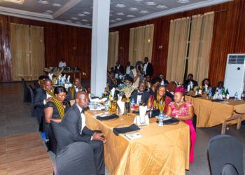 People seated at decorated banquet tables during a formal charity fundraising dinner
