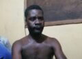 Emmanuel Gbayour seated shirtless during police questioning in Kakata, Liberia