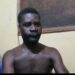 Emmanuel Gbayour seated shirtless during police questioning in Kakata, Liberia