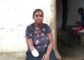 A woman with a bandaged arm sits outside her home in Todee District after a factory accident left her disabled.