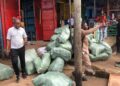 People standing near bundled goods in a busy market area during an eviction operation