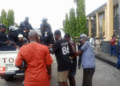 Police escorting defendants into a pickup truck outside the Temple of Justice following a contempt ruling related to a Supreme Court-ordered eviction in Paynesville.
