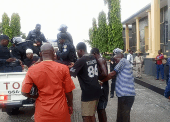 Police escorting defendants into a pickup truck outside the Temple of Justice following a contempt ruling related to a Supreme Court-ordered eviction in Paynesville.