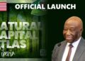 President Joseph Boakai smiling next to the official launch banner of the Natural Capital Atlas of Liberia.