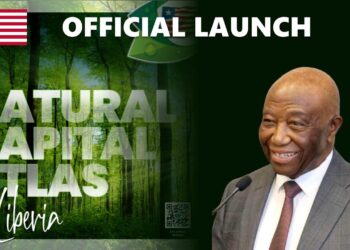 President Joseph Boakai smiling next to the official launch banner of the Natural Capital Atlas of Liberia.