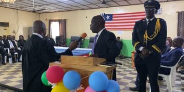Chief Justice Yamie Quiqui Gbeisay administers an oath during a court ceremony in Kakata, Margibi County, as officers and dignitaries look on under the Liberian flag