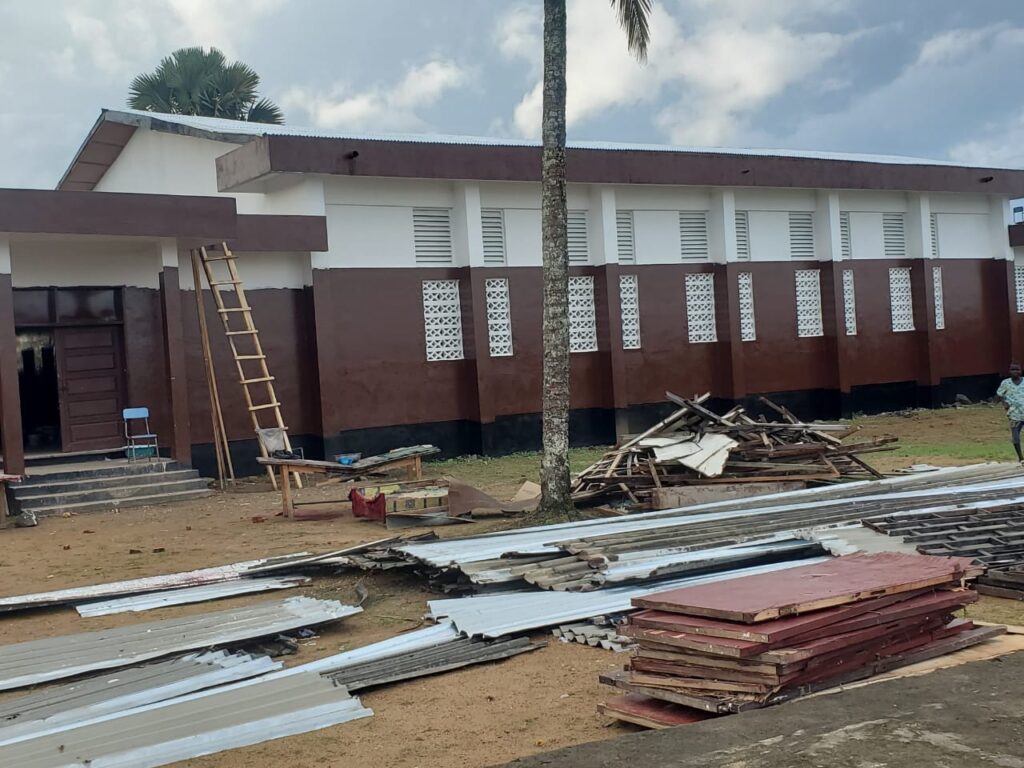 Workers installing panels at D. Twe High School during a renovation project criticized for substandard materials and poor supervision.