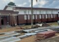 Workers installing panels at D. Twe High School during a renovation project criticized for substandard materials and poor supervision.