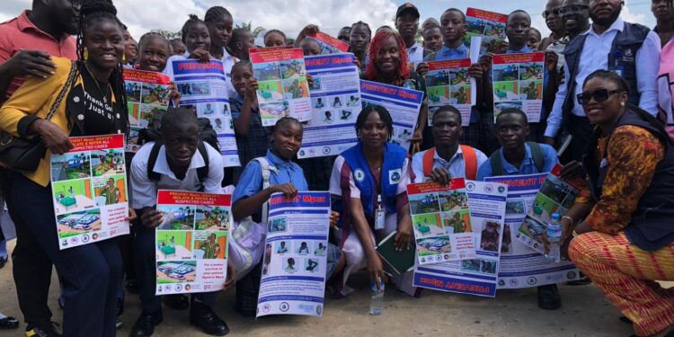 A group of students and community members holding public health awareness posters during an Mpox outreach campaign event